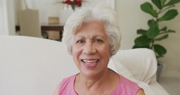 Portrait of smiling senior biracial woman looking at camera in living room