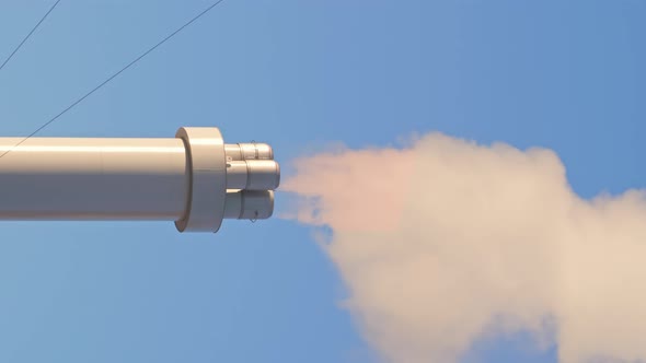 A large chimney of the plant is shot close, a lot of smoke comes out