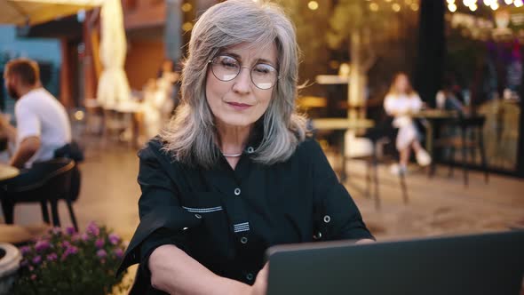 Grayhaired Attractive Business Woman a Business Owner Works in the Evening in a City Cafe