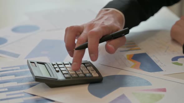 Close Up of Middle Aged Businessman Making Calculations Writing on Paper