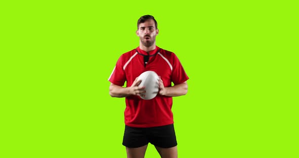 Professional Rugby Player Standing and Holding a Ball on Green Background