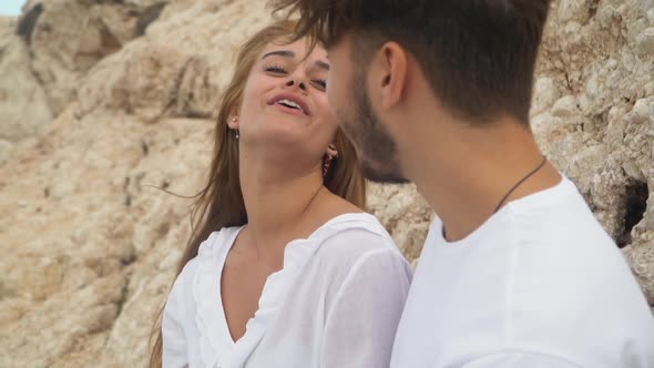 Young Couple Sitting Near a Rocky Shore Chatting Smiling Laughing and Having Fun