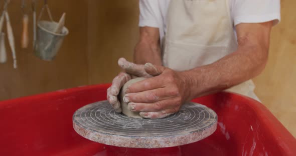 Senior caucasian man wearing apron making pottery in his workshop