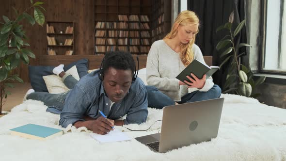 Black Guy and Blonde Girl Learn Together on the Bed