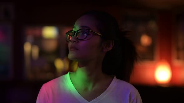 Young Beautiful Asian Woman With Eyeglasses Looking Around In The Club And Smiling