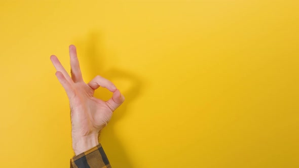Man's hand appears from below, shows the OK gesture. Yellow background.
