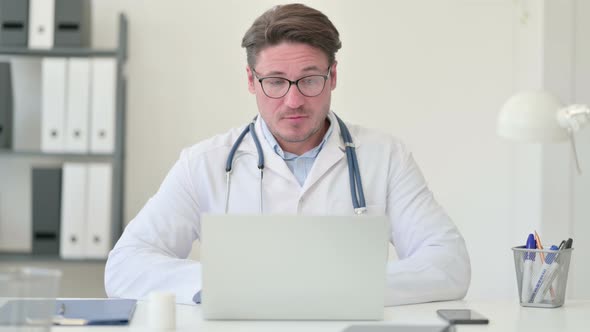 Video Call on Laptop By Middle Aged Male Doctor 