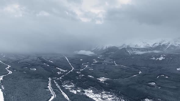 Drone flies over a frozen wooded valley in haze in Kananaskis, Alberta, Canada