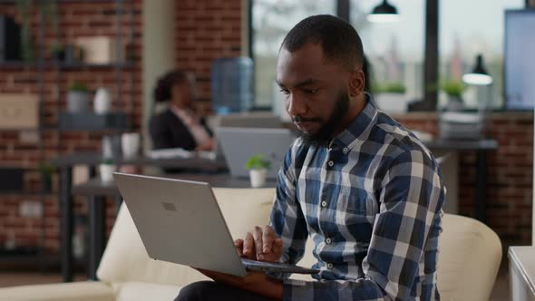 African American Worker Analyzing Financial Report on Laptop