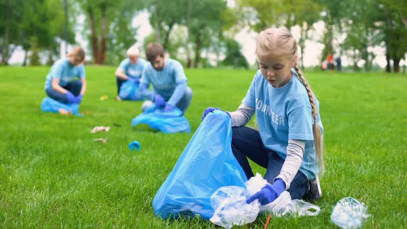 School Girl With Group of Eco Volunteers Picking Up Litter Park, Saving Nature