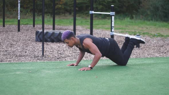 dolly shot going around a muscular guy who does knee push ups in an outdoor callisthenics sports par