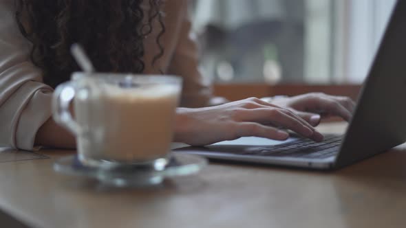 Woman Working And Typing On Laptop Computer With A Cup Of Hot Coffee alt