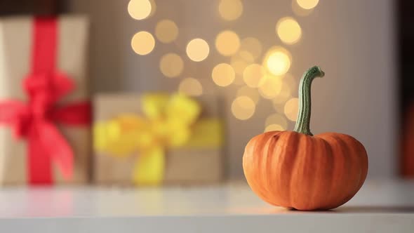 Pumpkin on table with gifts and fairy light on background