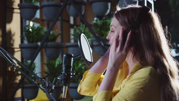 Woman in Headphones Recording Song on Studio