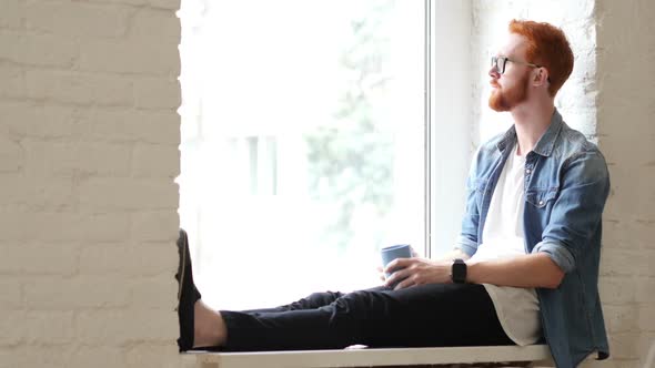 Pensive Designer Drinking Coffee, Sitting in Window, Red Hairs and Beard