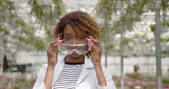 Woman Lab Technician Putting on Glasses at Green Plant