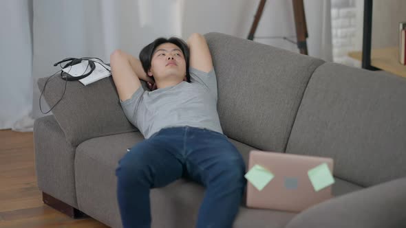 Thoughtful Young Startuper Thinking Lying on Couch in Living Room