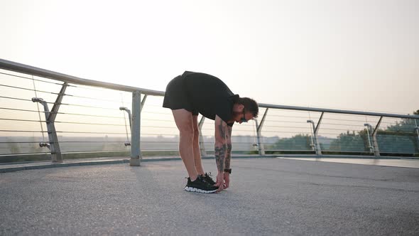 Active Man Does Squats Enjoying Workout on Footbridge