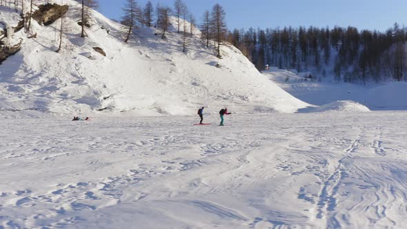 Aerial View of People Walking Across a Snow Covered Area in the Sun . Mountain Shadow Covering Part