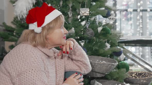 Senior Woman Smiling to the Camera While Sitting Near Christmas Tree at Home