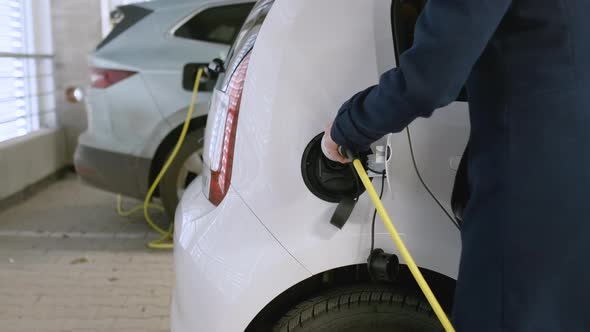 Business Woman Inserting a Charger Into the Electric Car at Charging Point in the Parking on the