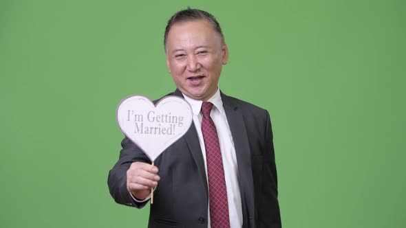 Mature Japanese Businessman Holding Paper Sign