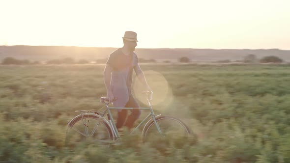 Man with Bicycle Walking through Grass