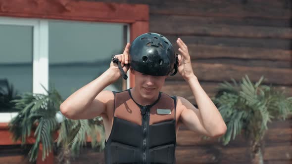 Young Man Putting On Watersports Helmet