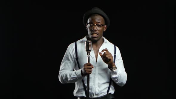 Man Singer Sings Into a Microphone and Dance. Black Background