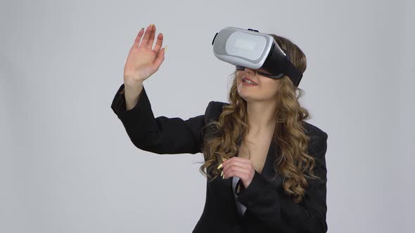 Woman with Virtual Reality Glasses on Her Head on Gray Background at Studio.