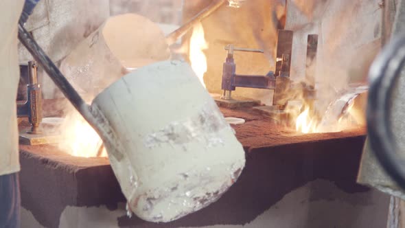 Workers in a foundry pouring liquid Aluminum to a sand cast