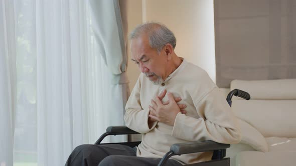 Asian Senior Elderly disabled man on wheelchair with chest pain suffer from heart attack in house.