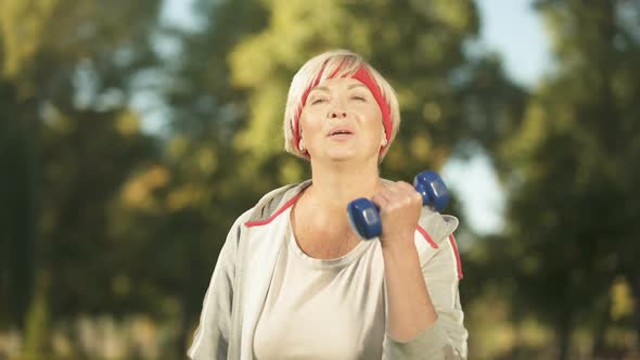 Happy Middle Aged Woman Doing Morning Workout With Dumbbells in Park, Health