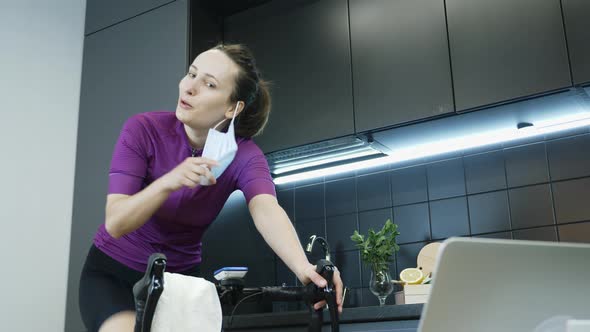 Portrait of young woman takes off protective medical face mask and smiling after hard cardio cycling