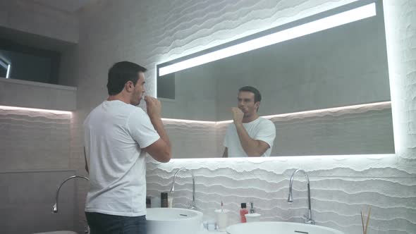 Happy Man Brushing Tooth in Bathroom. Concentrated Male Person Carrying Tooth