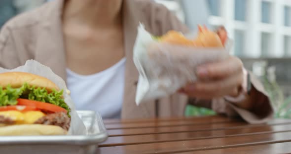 Woman eat with burger at outdoor coffee shop