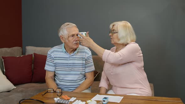 Senior Couple Measures Temperature with Contactless Digital Thermometer During Coronavirus Lockdown