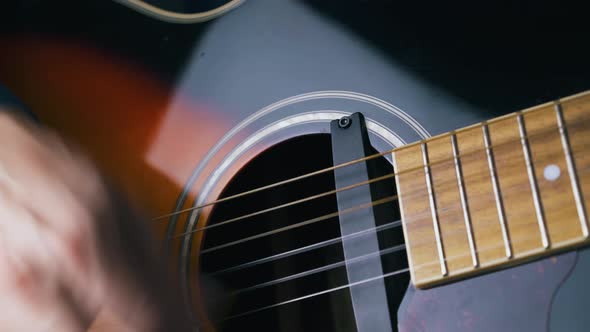 Person Plays Black and Brown Acoustic Guitar with Pick