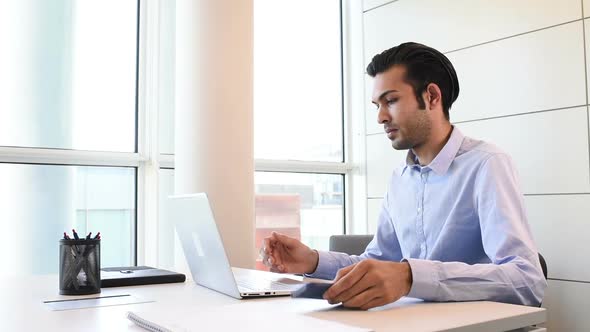 Young businessman indoor office interior using laptop computer and smart phone