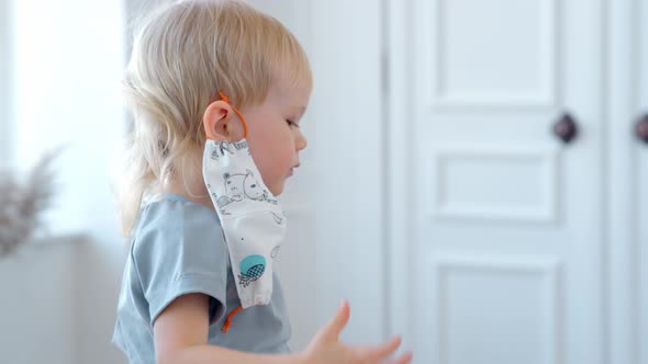 Little Boy Puts a Protective Mask on His Face