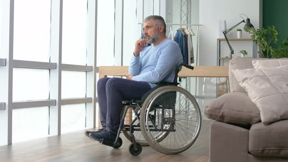 Man Looking Out the Window a Frustrated Mature Man Sitting in a Wheelchair