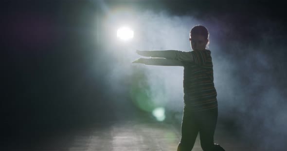 Young female dancer performing hip hop dance with strobe light and smoke background