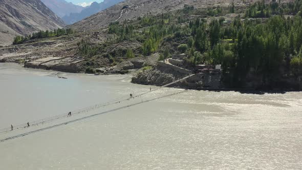 aerial drone of the famous Hussaini Bridge as tourists cautiously cross the bridge over a fast paced