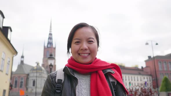 Front view of Asian woman standing and smiling on street in Sweden