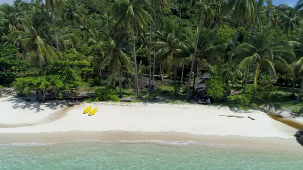 Drone shot of a tropical island beach with two yellow kayaks.
