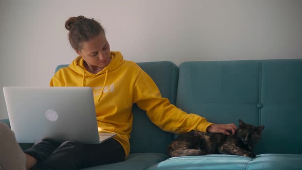 Young Woman Working the Home and Cuddling a Cat. 