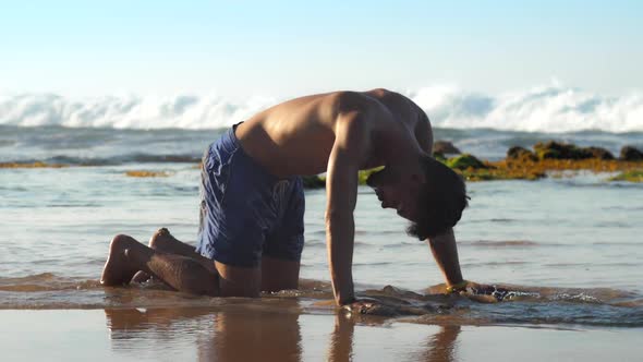 Barefoot Man Exercises in Water Against Foaming Ocean Waves