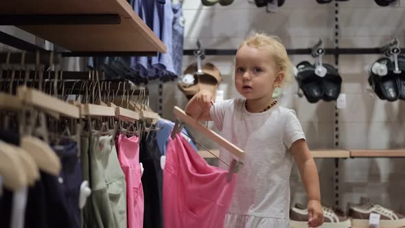 Adorable Cute Small Toddler Girl Choosing a Stylish Outfit in a Clothing Store Shopping Fashion