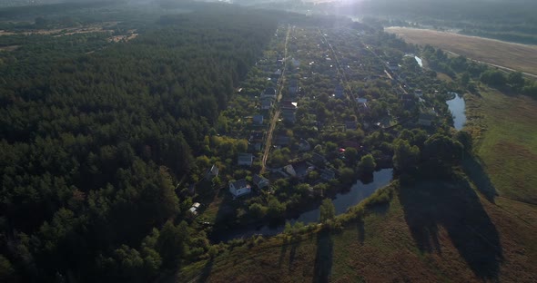 Drone Aerial View Small Village Between Forest and Field at Sunrise