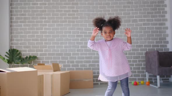 Cute little African American girl dance in living room with boxes or carton and she look fun